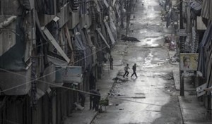 Sirios caminan junto a viviendas dañadas por la guerra civil en la ciudad de Alepo. (Foto AP)