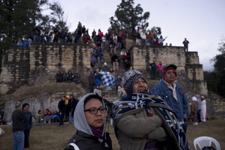 Algunas personas observan una ceremonia de la culminación del 13er baktún -o ciclo en el calendario de los mayas- en la zona arqueológica de Iximche, en Tecpan, Guatemala.