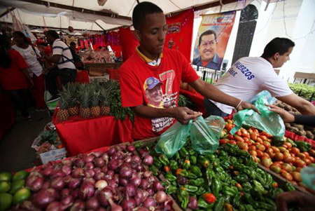 Un vendedor de vegetales trabaja vestido con una camiseta con la imagen del presidente Hugo Chávez en un mercado de administración estatal en Caracas el viernes 28 de diciembre del 2012.