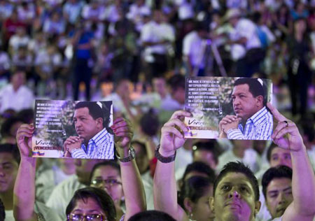 Un par de personas sostienen imágenes del presidente venezolano Hugo Chávez durante un concierto para apoyarlo en Managua, Nicaragua, el lunes 17 de diciembre