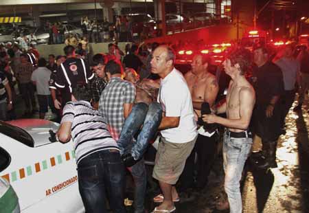 Un hombre carga a un herido en un incendio en un club nocturno en la ciudad de Santa María, en el estado de Rio Grande do Sul en Brasil, la madrugada del domingo 27 de enero de 2013.