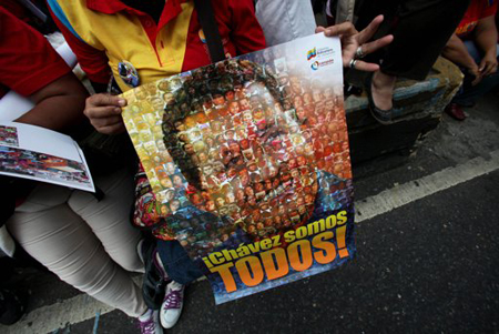 Un simpatizante del presidente venezolano Hugo Chávez sostiene un poster con la imagen del gobernante con la frase "Chávez somos todos" en una manifestación a favor del mandatario en Caracas, Venezuela, el miércoles 23 de enero de 2013.