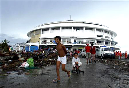En la imagen, unos niños juegan a las afueras de un centro de convenciones en Tacloban, convertida en un albergue para refugiados del tifón Haiyan.