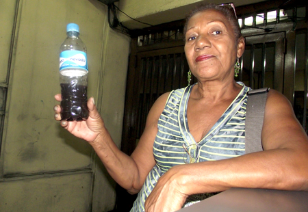 Bernarda Suárez muestra a la cámara el agua sucia con la que cuenta el edificio en donde reside 