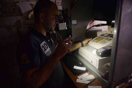 A cashier at a minimarket uses his cell phone as a flashlight during::AFP PHOTO:LEO RAMIREZ