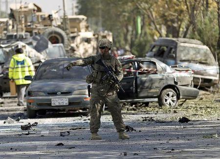 Un soldado de EE.UU hace guardia cerca de un vehículo dañado en el lugar del ataque suicida en Kabul