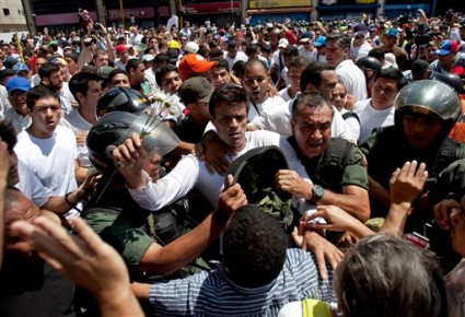 En esta foto de archivo del 18 de febrero de 2014, el líder opositor Leopoldo López, vestido de blanco y alzando una flor, es arrestado por la GNB en Caracas, Venezuela. Ha pasado un año desde las protestas contra el gobierno que dejharon 43 muertos. El miércoles 18 de febrero de 2015, López cumplió un año en la cárcel. (AP Foto)