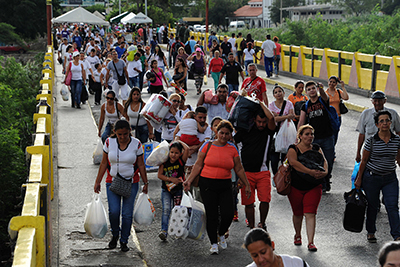 Venezuelans carrying groceries cross the Simon Bolivar bridge from Cucuta in Colombia back to San Antonio de Tachira in Venezuela, on July 10, 2016. Thousands of Venezuelans crossed Sunday the border with Colombia to take advantage of its 12-hour opening after it was closed by the Venezuelan government 11 months ago. Venezuelans rushed to Cucuta to buy food and medicines which are scarce in their country. / AFP PHOTO / GEORGE CASTELLANOS