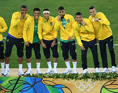 Brazil's players including Neymar (C) celebrate on the podium during the medal presentation following the Rio 2016 Olympic Games men's football gold medal match between Brazil and Germany at the Maracana stadium in Rio de Janeiro on August 20, 2016.  / AFP PHOTO / Johannes EISELE