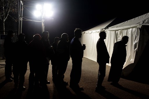 Iluminados gracias a un generador portátil, varios votantes hacen fila frente a una carpa acondicionada como puesto de votación en la sección Midland Beach de Staten Island, Nueva York. (Foto AP)