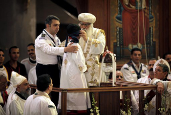 El patriarca copto en funciones Pacomios, centro, venda los ojos al muchacho que sacó la papeleta con el nopmbre de un cáliz de cristal en la catedral copta de El Cairo el domingo 4 de noviembre del 2012.