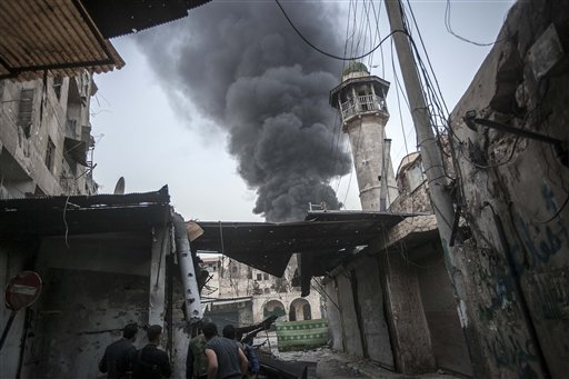 Combatientes insurgentes observan una columna de humo después de que fuerzas del gobierno sirio atacaron con artillería una posición rebelde en Alepo, Siria.