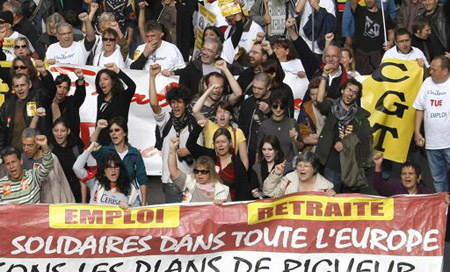 Trabajadores marchan y vociferan mientras portan una manta con la leyenda "Empleo. Pensión. Unidos en Europa"