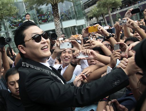 El rapero sudcoreano PSY, intérprete de la popular canción "Gangnam Style", saluda a admiradores tailandeses tras una conferencia de prensa en Bangkok, Tailandia. Ahora que el "Gangnam Style" se aproxima a los 1.000 millones de reproducciones en YouTube, PSY, el primer artista pop asiático que ha cautivado al público mundial, se ha hecho rico clic por clic, al igual que su agente.
