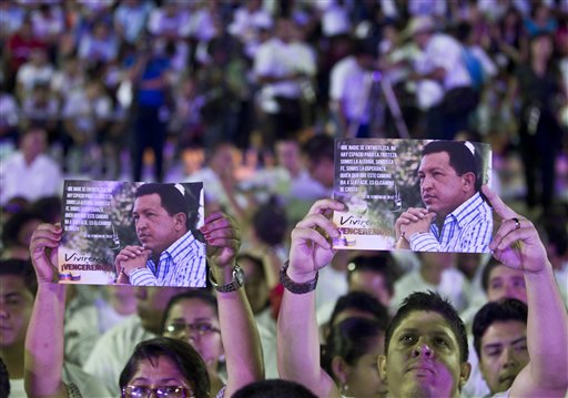 Un par de personas sostienen imágenes del presidente venezolano Hugo Chávez durante un concierto para apoyarlo en Managua, Nicaragua, el lunes 17 de diciembre de 2012. Chávez muestra mejoría tras su cuarta cirugía por cáncer, informó el martes 18 de diciembre el ministro del Exterior de Brasil. (Foto AP/Esteban Felix)