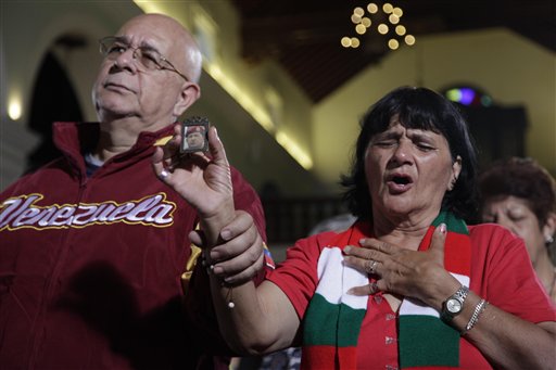 Un grupo de personas, incluida una mujer con una foto del presidente Hugo Chávez, ora en Caracas, el lunes 31 de diciembre de 2012 (AP Foto/Ariana Cubillos)