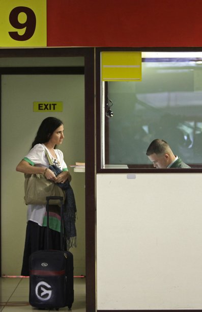 La bloguera cubana disidente Yoani Sánchez en su salida hacia Brasil y otros países muestra su pasaporte en migración en el aeropuerto José Martí de La Habana, Cuba, el domingo 17 de febrero de 2013.