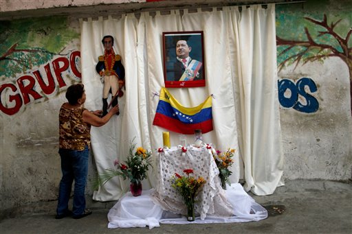 Una mujer coloca una imagen del libertador Simón Bolívar junto a una foto de Hugo Chávez en un improvisado altar callejero en Caracas el 14 de marzo del 2013. La oposición dice que el oficialismo está explotando la imagen del finado presidente con miras a las elecciones del mes que viene. (AP Photo/Rodrigo Abd)