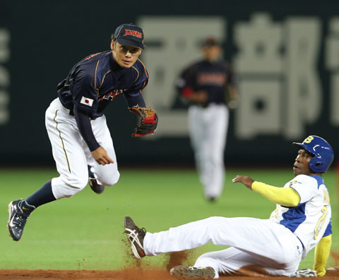 El segunda base de Japón, Takashi Toritani, lanza a primera para completar una doble matanza ante la barrida del brasileño Jc Muñiz Foto: AP/Koji Sasahara