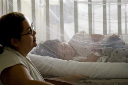 Una madre pendiente de su hijo hospitalizado con dengue en El Salvador.