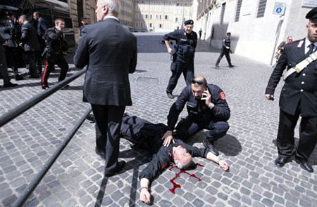 Uno de dos policías heridos de bala yace en el suelo afuera de la oficina del primer ministro en Roma, el domingo 28 de abril de 2013.