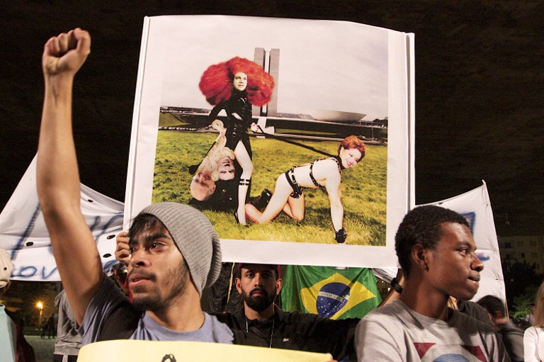 Un manifestante sostiene el cartel que contiene un montaje fotográfico con el presidente de Brasil, Dilma Rousseff (D) y el Congresista Marco Feleciano (I). Foto: AFP