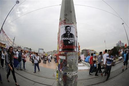 Varias personas pasan junto a un afiche con la imagen del primer ministro turco, Tayip Erdogan, en la plaza Taksim en Estambul, el 7 de junio de 2013.