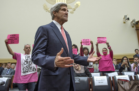 El secretario de Estado de Estados Unidos, John Kerry, pasa junto a manifestantes contrarios a una intervención en Siria en la audiencia del miércoles ante un panel del Senado en Washington.