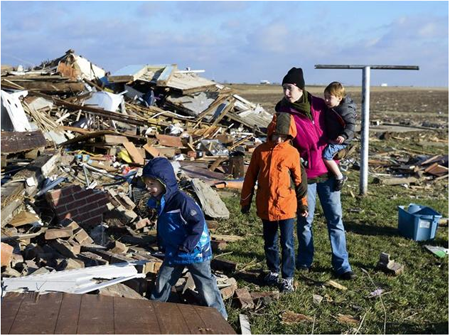 Una familia observa los restos de su hogar, destruido a causa de un tornado en Washington (Illinois), Estados Unidos