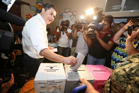 En esta fotografía difundida por el Partido Nacional, el candidato presidencial de esa fuerza oficialista Juan Orlando Hernández deposita su voto en una urna de un centro de votación en Lempira.