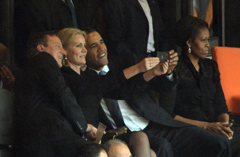 EE.UU. El presidente Barack Obama (R) y el primer ministro británico, David Cameron posan para una foto selfie con el primer ministro de Dinamarca Helle Thorning Schmidt (C) junto a EE.UU. la primera dama Michelle Obama (R) durante la ceremonia conmemorativa del sudafricano ex presidente Nelson Mandela en el Estadio FNB (Soccer City) en Johannesburgo el 10 de diciembre de 2013. Mandela, el icono venerado de la lucha contra el apartheid en Sudáfrica y una de las imponentes figuras políticas del siglo 20, murió en Johannesburgo el 05 de diciembre a los 95 años. AFP PHOTO / ROBERTO SCHMIDT