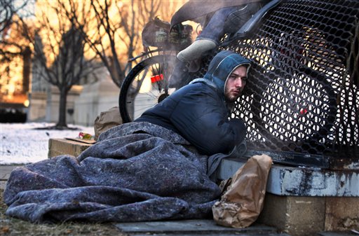 Nicholas Simmons, de 20 años, de Greece, un pueblo del estado de Nueva York, busca el calor de una rejilla de vaporcon otros tres desamparadosen la Comisión Federal de Comercio, a pocas cuadras del Capitolio en Washington, el sábado 4 de enero del 2014. Nicholas Simmons desapareció de la casa de sus padres en un pequeño pueblo del estado de Nueva York el Día de Año Nuevo, dejando su billetera, su teléfono celular y todas sus pertenencias. Cuatro días después una fotógrafa de Associated Press, que buscaba escenas para ilustrar el inclemente frío que asolaba la región, le tomó la foto y su familia lo reconoción en una edición dominical del US Today. El padre de Simmons, Paul, y un hermano mayor Paul, llegaron a Washington el domingo por la noche5 de enero y se reunieron con Simmons en el hospital al que había sido trasladado por la policía. (Foto AP/Jacquelyn Martin))