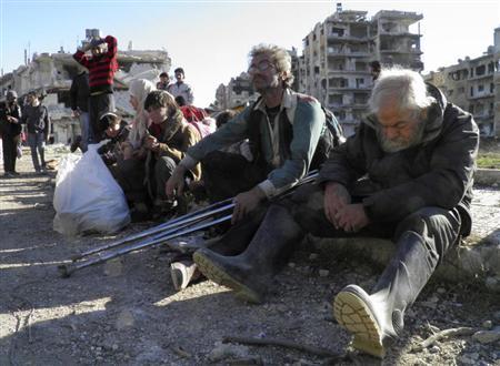 En la imagen, varios civiles sentados con sus pertenencias esperan sentados para ser evacuados de una zona de la ciudad siria de Homs bajo asedio, el 12 de febrero de 2014.