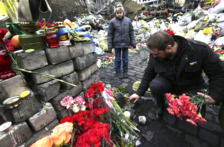 Una persona junto a un memorial artesanal dedicado a los fallecidos en los recientes hechos de violencia acontecidos en Kiev.