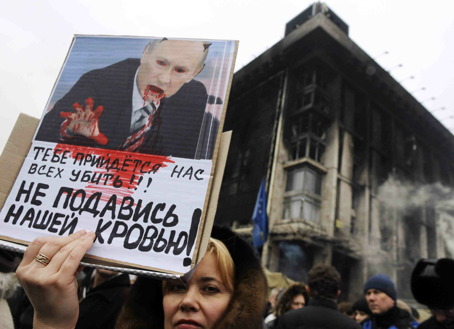 Ucrania, Kiev: Una mujer sostiene un cartel que representa el presidente ruso, Vladimir Putin, como el diablo con la lectura del texto "Tendrá que matar a todos nosotros, no nos ahogan con nuestra sangre" durante una manifestación titulada "Ucrania y Crimea están juntos" en Kiev , el 2 de marzo de 2014. Ucrania advirtió hoy que estaba al borde del desastre y llamó a todos los reservistas militares después de la amenaza de Rusia de invadir a su vecino llamó reprensiones fuertes de Estados Unidos y sus aliados occidentales. AFP PHOTO / YURIY DYACHYSHYN