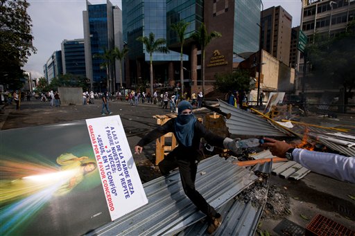 Un manifestante antigubernamental enmascarado se para sobre una barricada durante enfrentamientos con la policía nacional bolivariana en Caracas el 1ro de abril del 2014. (AP Photo/Fernando Llano)