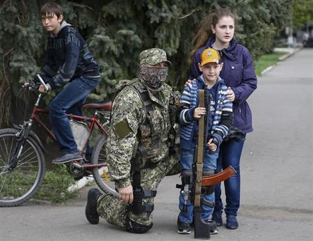 Residentes locales posan para una fotografía con un homrbe armado afín a Moscú frente a la oficina del alcalde en Slaviansk, en Ucrania. 20 de abril, 2014.