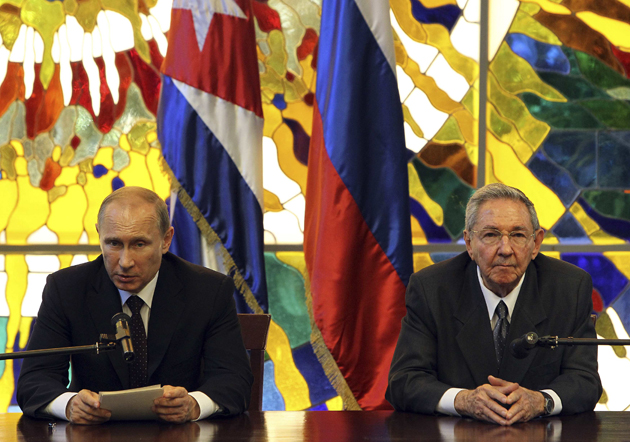 Russia's President Vladimir Putin (L) reads a document next to Cuba's President Raul Castro after a meeting at the Revolution Palace in Havana July 11, 2014. Putin met former Cuban leader Fidel Castro and current President Raul Castro on Friday to begin a six-day tour of Latin America in which Russia is seeking to reassert its influence on the communist-ruled island.  REUTERS/Alejandro Ernesto/Pool (CUBA - Tags: POLITICS)