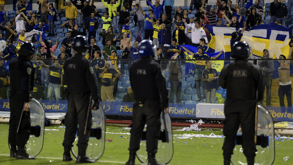 Boca Juniors' supporters shouts while policeman stand on the field before Argentina's River Plate team leaves the pitch after the match was suspended when Boca Juniors'  fans pepper sprayed River Plate players before the start of the second half of the Copa Libertadores 2015 second leg football match against Argentina's Boca Juniors at the "Bombonera" stadium in Buenos Aires, Argentina, on May 15, 2015. AFP PHOTO / JUAN MABROMATA        (Photo credit should read JUAN MABROMATA/AFP/Getty Images)