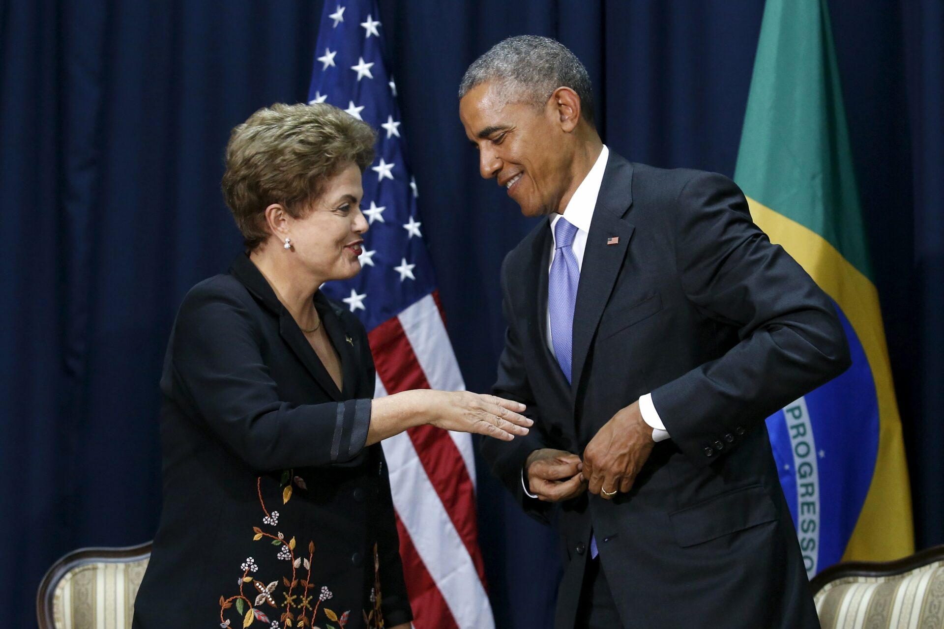 U.S. President Barack Obama hurries to button his jacket before shaking hands with Brazil's President Dilma Rousseff at their meeting during the Summit of the Americas in Panama City, Panama April 11, 2015. REUTERS/Jonathan Ernst
