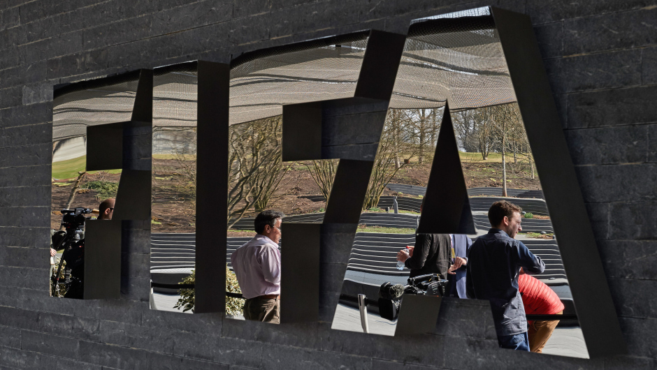 Member of the media wait next to a logo of the Worlds football governing body, at the FIFA headquarters in Zurich, prior to a press conference of FIFA President Sepp Blatter on March 20, 2015, closing a two-day meeting to decide the dates of the 2022 World Cup in Qatar. AFP PHOTO / MICHAEL BUHOLZER        (Photo credit should read MICHAEL BUHOLZER/AFP/Getty Images)
