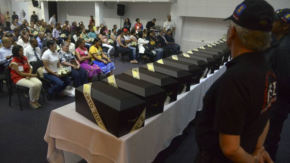 People take part in a ceremony in the framework of the country's peace process in Medellin, Antioquia department, Colombia on August 29, 2014. Relatives of 19 victims received the remains of their loved ones, who were recently found in a mass grave, thanks to information provided by demobilized from both sides, the leftist guerrillas and the right-wing paramilitaries groups.  AFP PHOTO/Raul ARBOLEDA        (Photo credit should read RAUL ARBOLEDA/AFP/Getty Images)