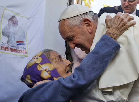 Pope Francis is greeted by a Catholic faithful during his visit to the Banado Norte neighborhood in Asuncion, on July 12, 2015. Pope Francis visted the poorest neighborhood of Paraguay before ending his Latin American tour. AFP PHOTO / POOL - GREGORIO BORGIA