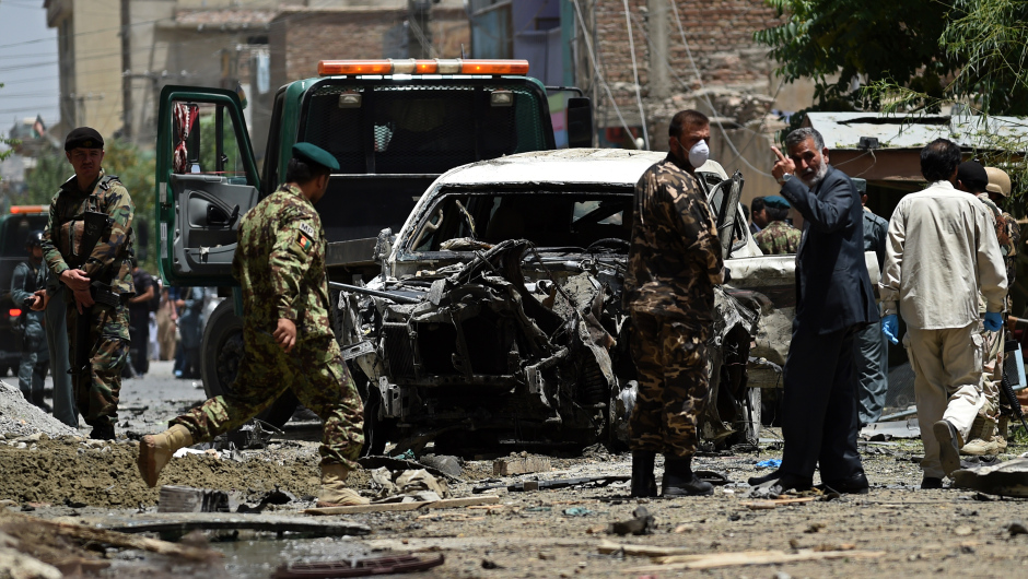 Afghan security forces inspect a damaged vehicle at the site of a bomb blast that targeted NATO forces in Kabul on July 7, 2015. A bomb blast targeted NATO forces in Kabul, a spokesman for the coalition told AFP, as the Taliban step up attacks as part of their annual summer offensive. AFP PHOTO / WAKIL KOHSAR        (Photo credit should read WAKIL KOHSAR/AFP/Getty Images)