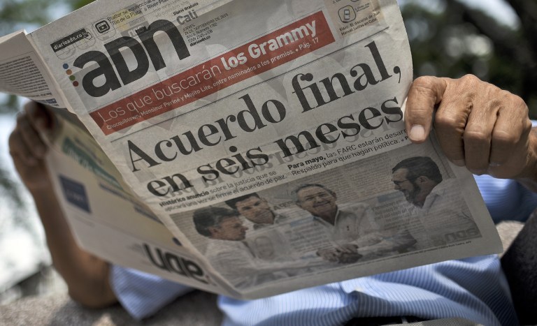 A man reads a newspaper which shows in the front page a picture of the agreements achieved between the Government and FARC rebels in Cuba on September 24, 2015, in Cali, Colombia. Colombian President Juan Manuel Santos and Timoleon "Timochenko" Jimenez, the leader of the FARC rebels, announced a major breakthrough on Wednesday in peace talks to end a conflict that has burned for half a century. AFP PHOTO / LUIS ROBAYO