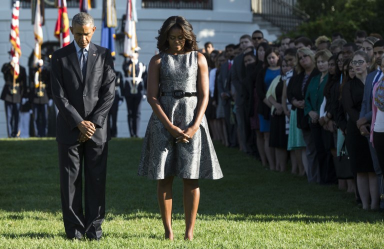 US President Barack Obama and First Lady Michelle Obama observe a moment of silence on the South Lawn of the White House in Washington, DC, September 11, 2015, to mark the 14th anniversary of the 9/11 attacks on the United States. AFP PHOTO / SAUL LOEB