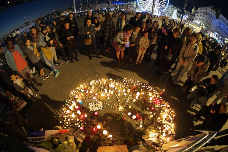 TOPSHOTSPeople gather on November 15, 2015 at a makeshift memorial in the "Vieux port" of Marseille, for the victims of November 13 attacks in Paris. Islamic State jihadists claimed a series of coordinated attacks by gunmen and suicide bombers in Paris that killed at least 132 people in scenes of carnage at a concert hall, restaurants and the national stadium. AFP PHOTO / BORIS HORVAT
