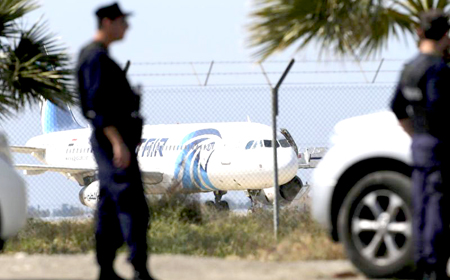 Agentes de policía hacen guardia junto a la valla de un aeropuerto con el avión secuestrado de EgyptAir en segundo plano, en el aeropuerto de Larnaca, en Chipre, el 29 de marzo de 2016.