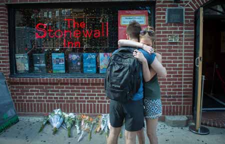 In reaction to the mass shooting at a gay nightclub in Orlando, Florida people hug outside the Stonewall Inn near a vigil for the victims in New York on June 12, 2016. Fifty people died Sunday when a gunman allegedly inspired by the Islamic State group opened fire inside a gay nightclub in Florida, in the worst terror attack on US soil since September 11, 2001. / AFP PHOTO / Bryan R. Smith
