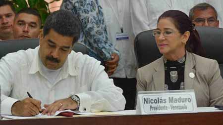 El mandatario al momento de suscribir el histórico documento; a su lado la Primera Dama Cilia Flores.